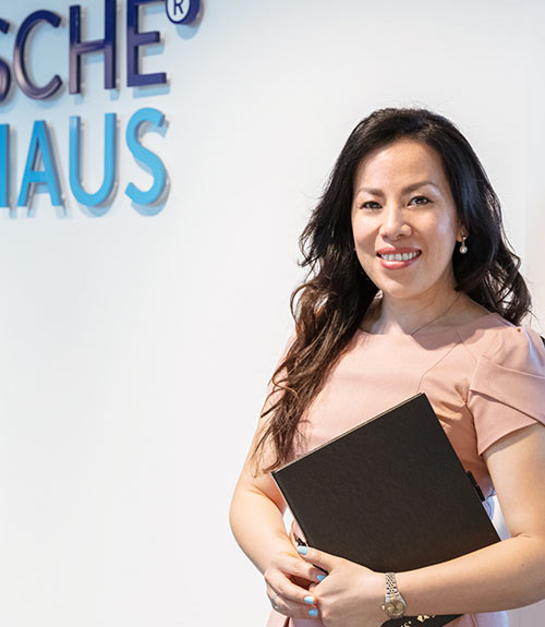 Das Foto zeigt eine Angestellte der Deutsche Zinshaus mbH. Sie steht mit einem Ordner vor dem Logo der Firma.Das Foto zeigt eine Angestellte der Deutsche Zinshaus mbH. Sie steht mit einem Ordner vor dem Logo der Firma.